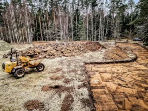 Greeneris specialistai pašalina augalinį dirvos sluoksnį prieš statant krepšinio aikštelę.