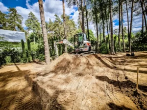 Greeneris sunkiasvorės technikos specialistas lygina pagrindus su Bobcat mini krautuvu.