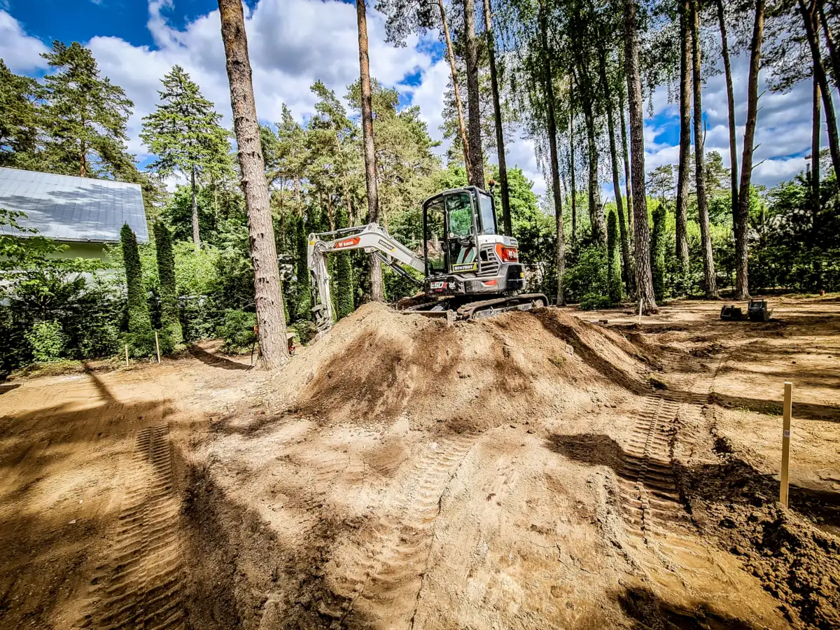 Greeneris sunkiasvorės technikos specialistas lygina pagrindus su Bobcat mini krautuvu.