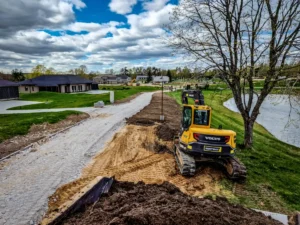 Greeneris specialistai su ekskavatoriumi formuoja reljefą ir tvarko šlaitus būsimam vejos įrengimui.